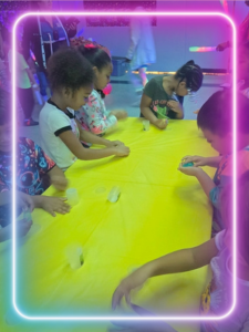 kids standing around a yellow table 